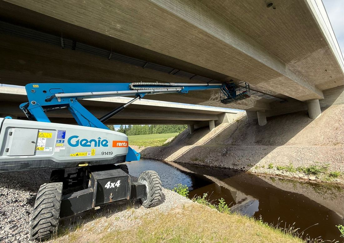 Henkilönostin puron rannalla betonisillan alla, työkori kannen alapinnassa.