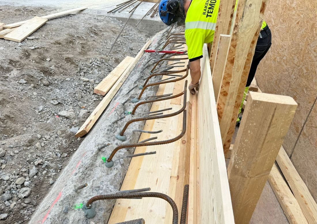 Työntekijä reunapalkin muottityössä, raudoitustartunnat rivissä.